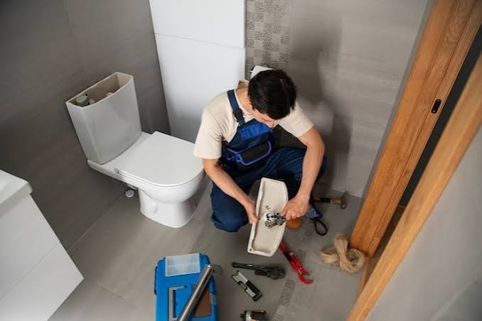 Plumber repairing bathroom pipework and connections